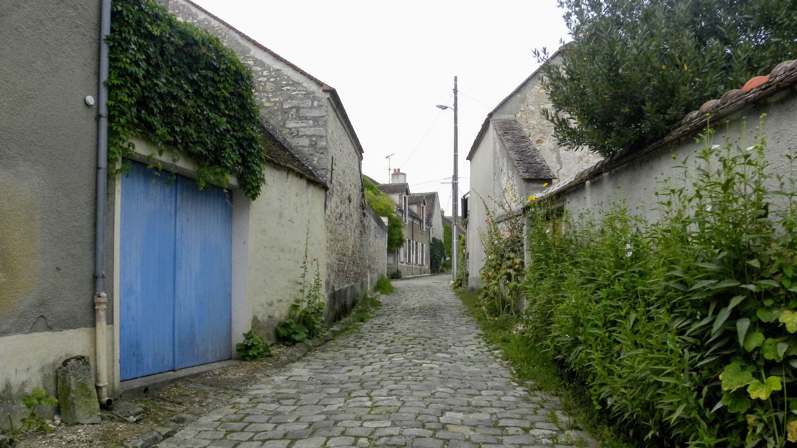 石造りの倉庫や家に挟まれた、石畳の小道。
