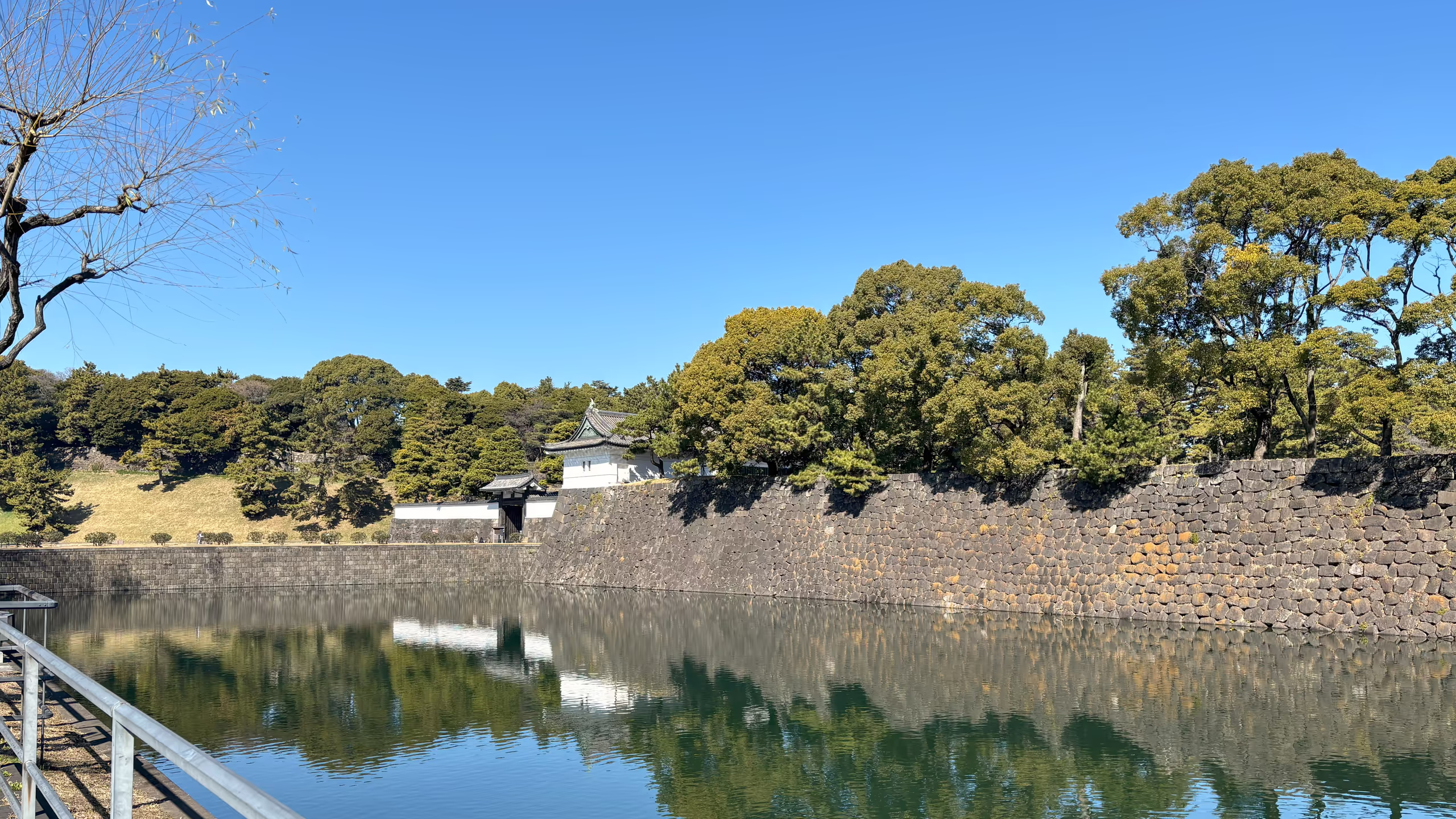 広い堀の奥に石垣、石垣の上に櫓、櫓の横に門と並ぶ