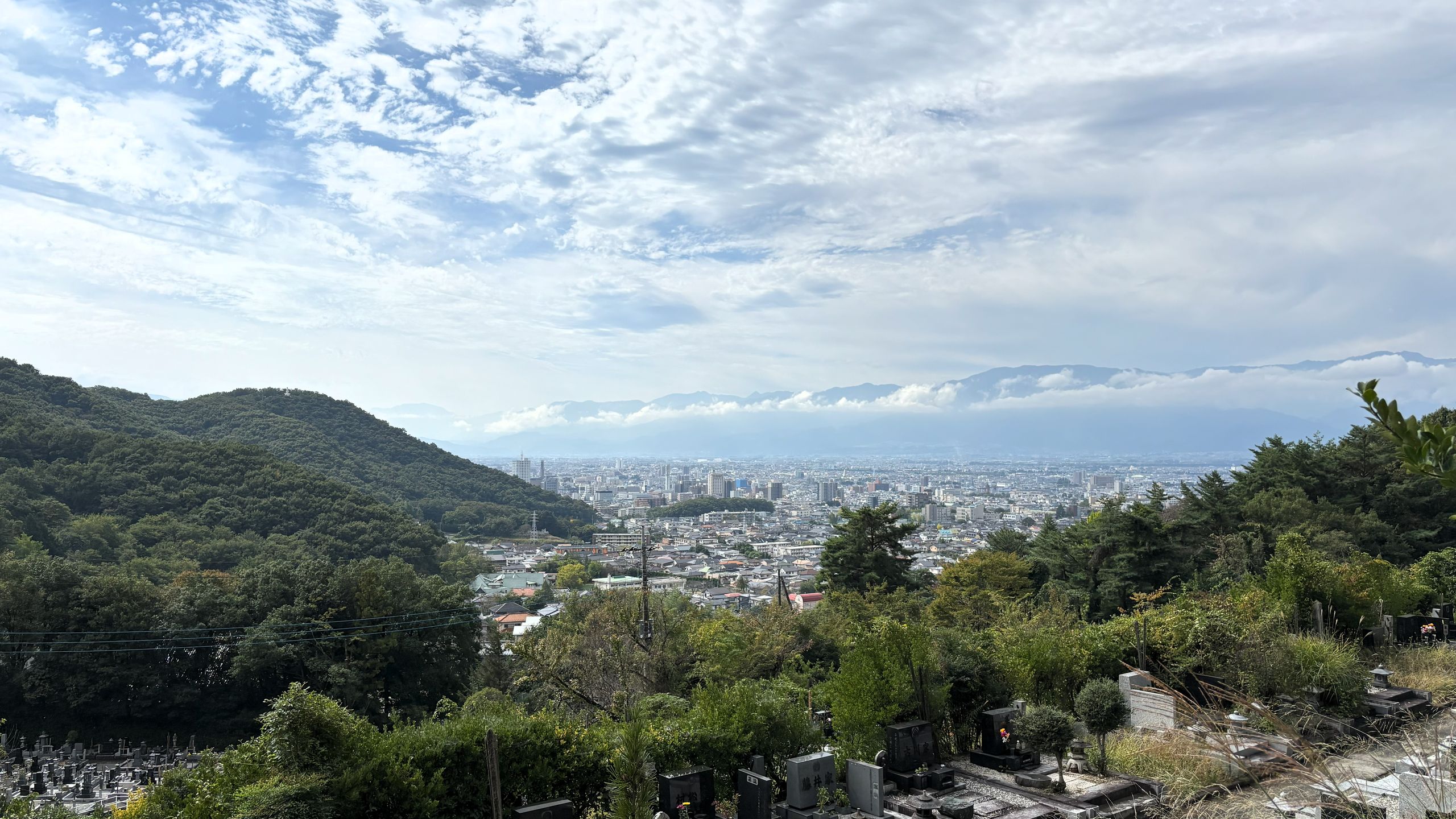 霊園の木々はまだ緑が濃く、紅葉はまだ始まっていない。眼下に広がる甲府を囲む山々は雲に覆われ、見ることができない。