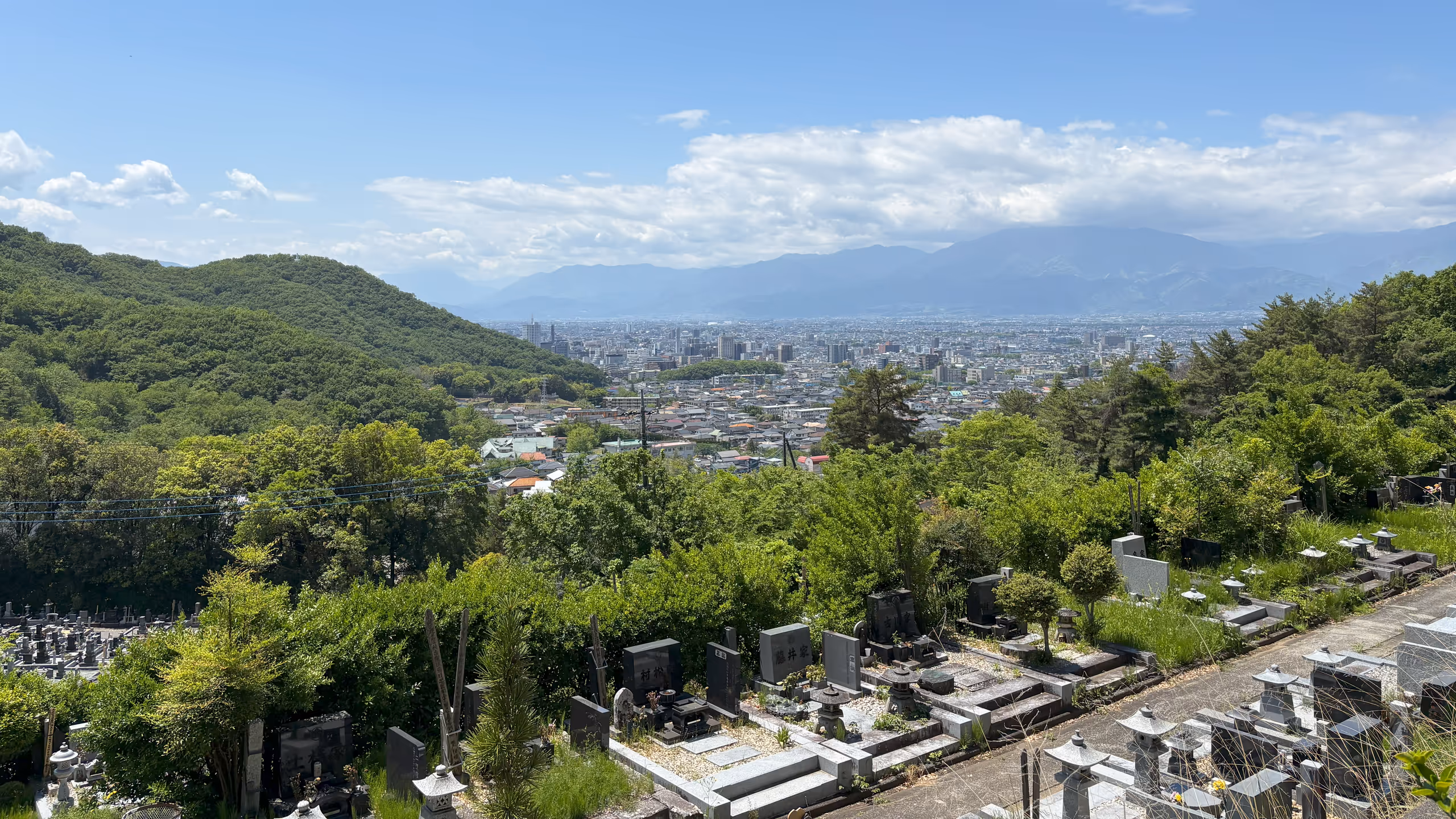 山々には雲がかかるものの、良く晴れている。高台から見下ろす市街地がもやもなくはっきりと見える。墓地や周囲の山はまさに新緑という鮮やかさだ。