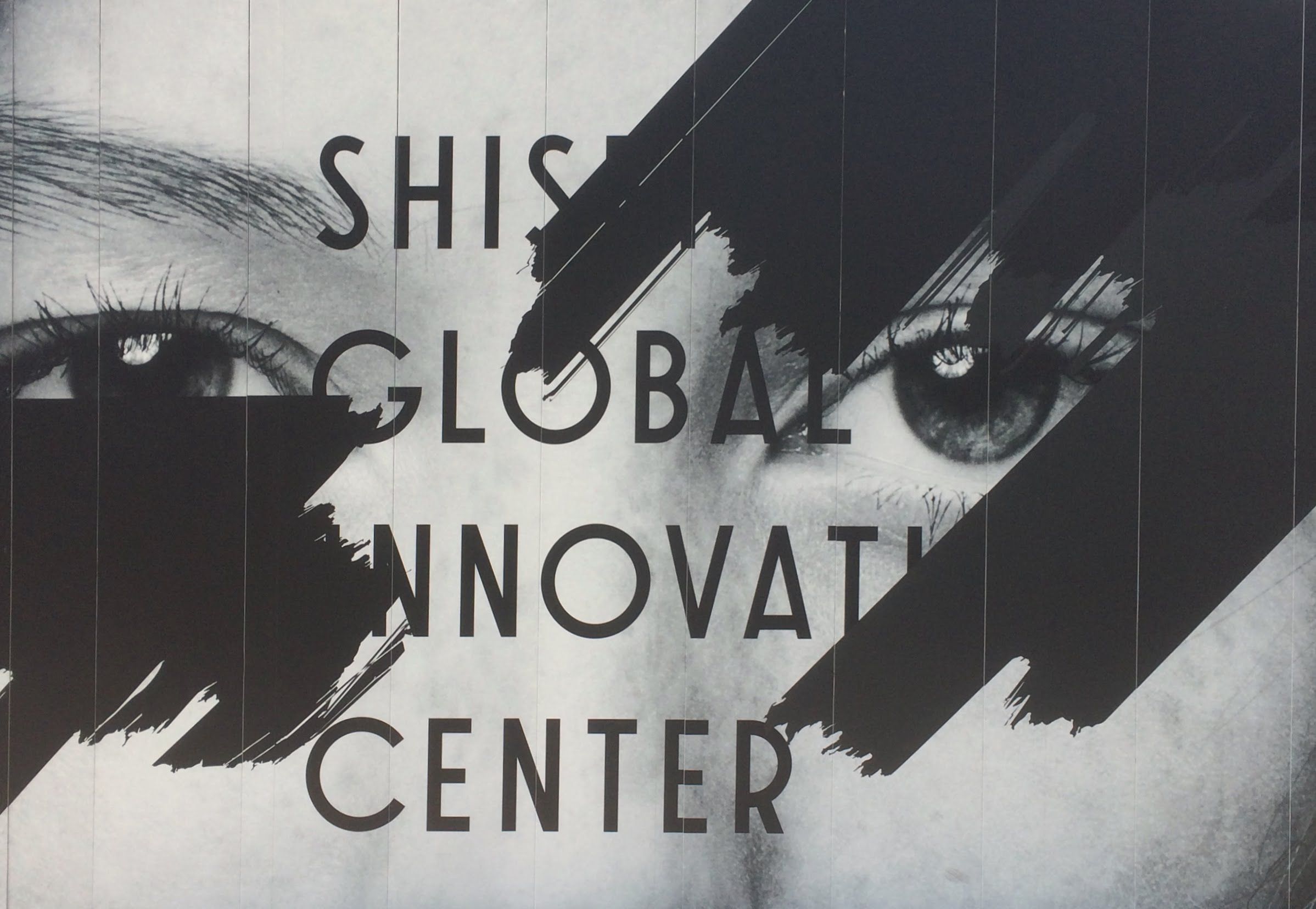 モノクロの顔写真にShiseido Global Innovation Centerの文字を重ね、上から黒のブラシで少し塗りつぶしたプリント。