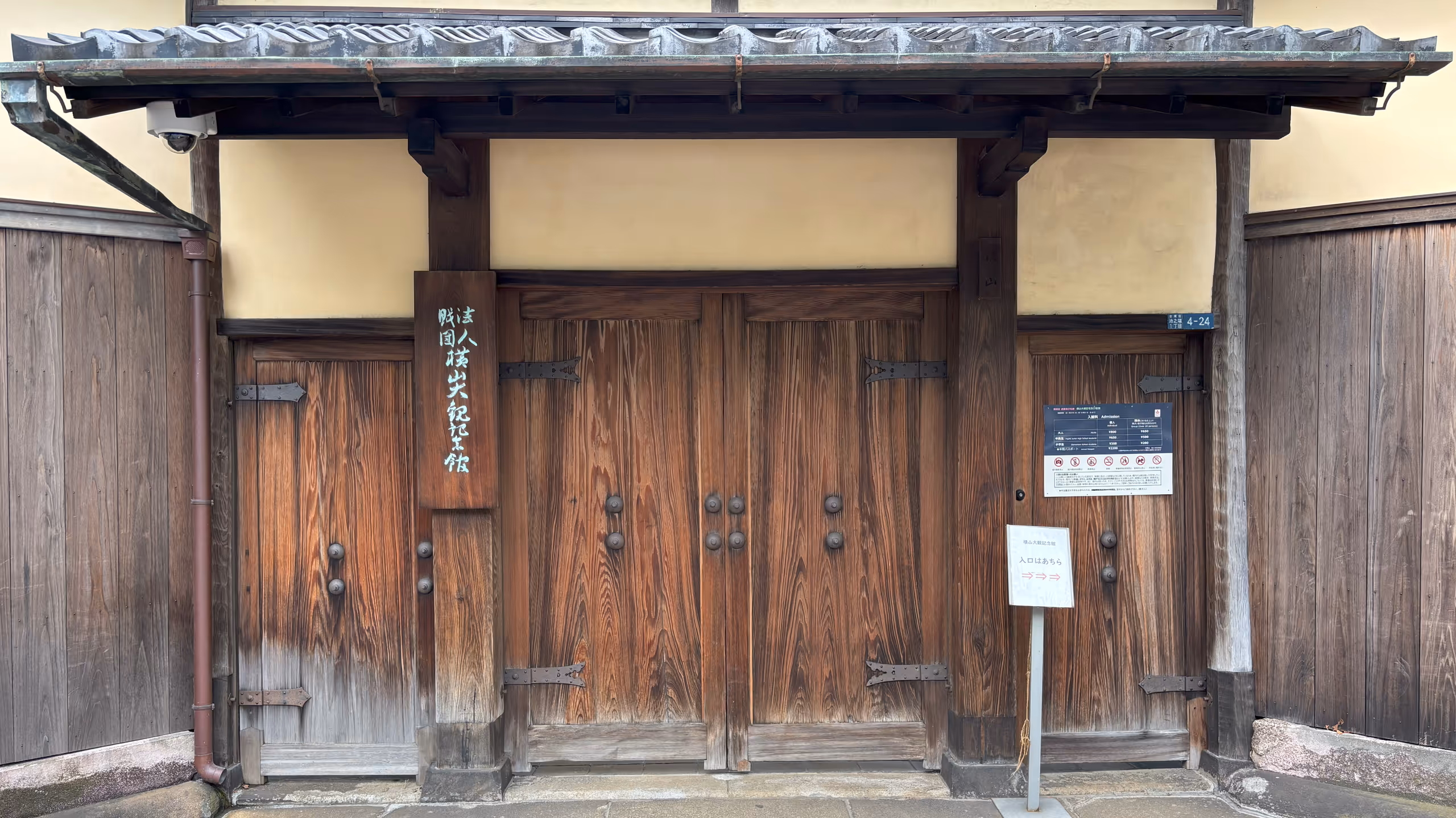 瓦葺の屋根を支える柱の間は、土壁の下に両開きの大きな木製の扉がある。