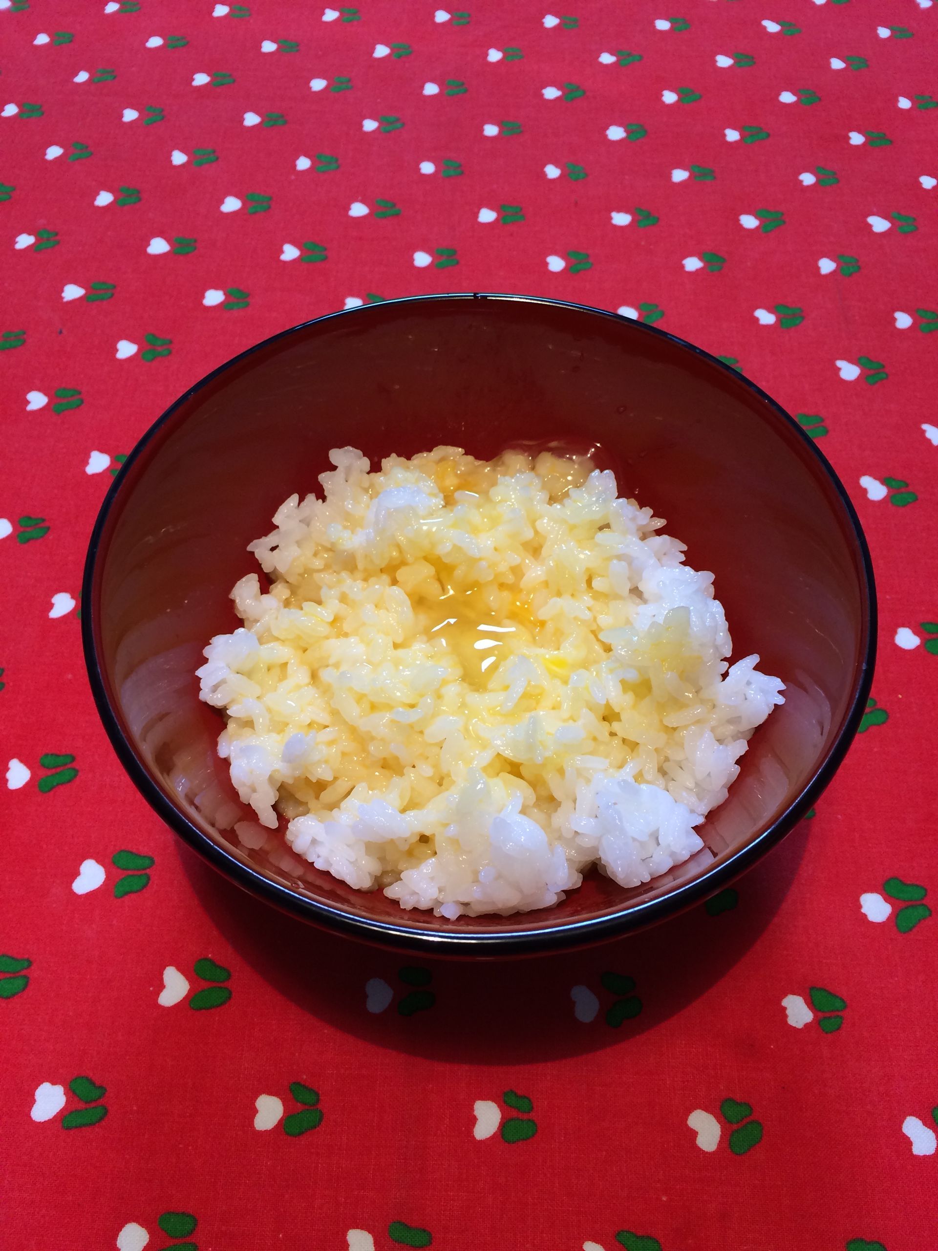 内側が赤、外側が黒の塗丼に白いご飯が盛られ、その上へよくかき混ぜられた卵がかけられている。
