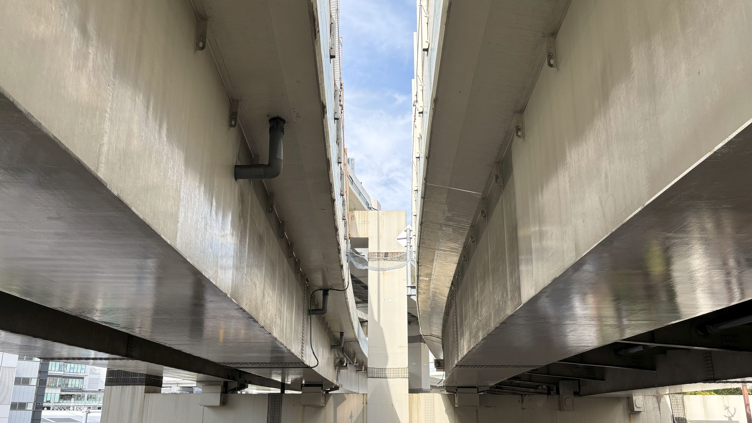 上りと下りの高架道路に挟まれた狭い隙間から、薄雲のかかった青空がのぞいている。